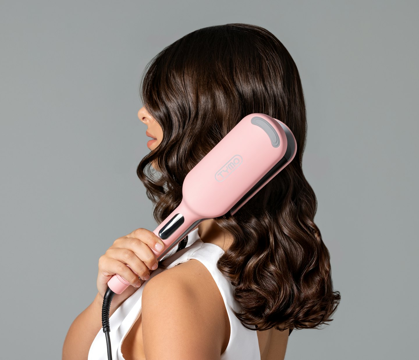 Person using a pink and black hair styling tool on their hair.