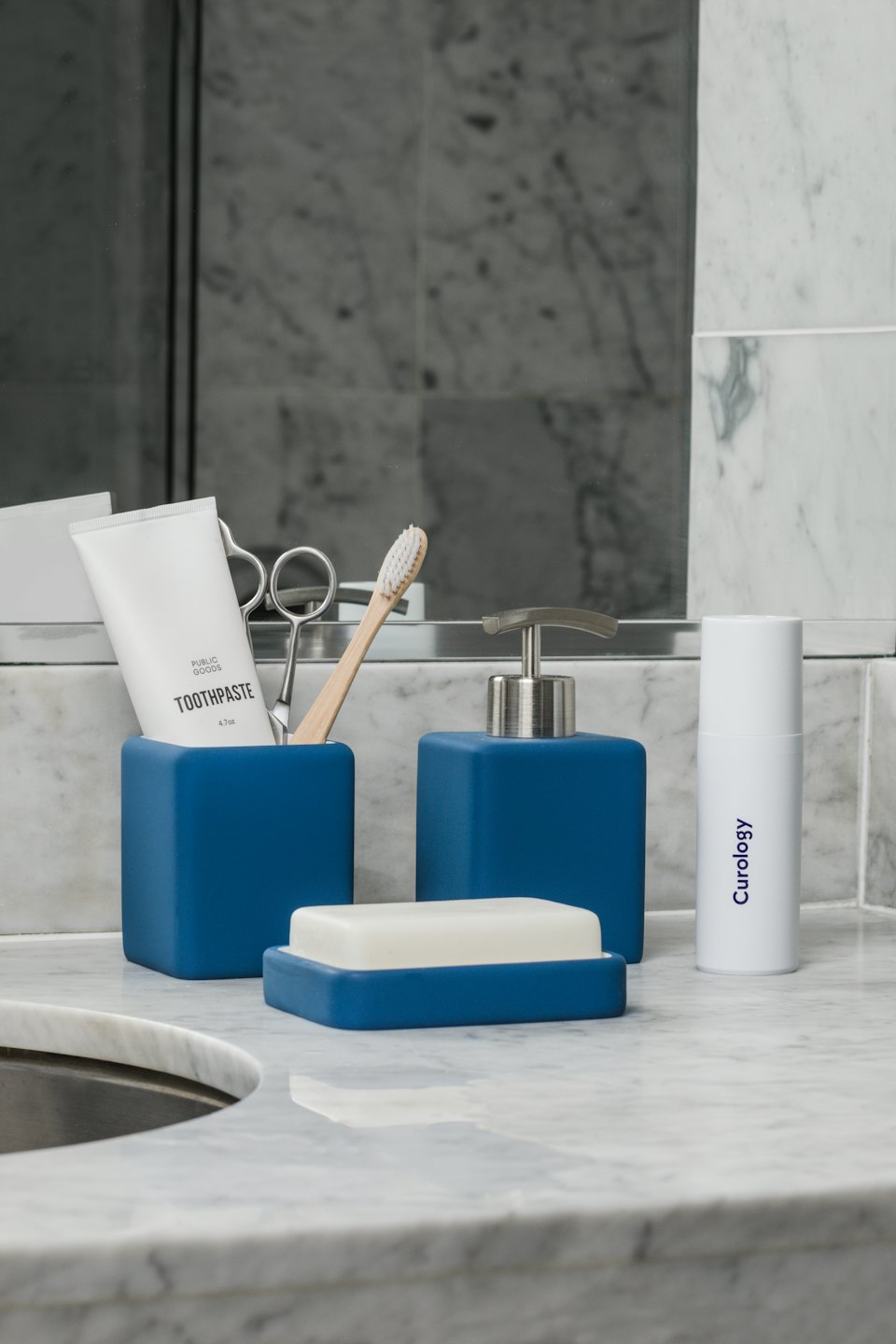 Minimalist blue and white bathroom accessories on marble countertop.